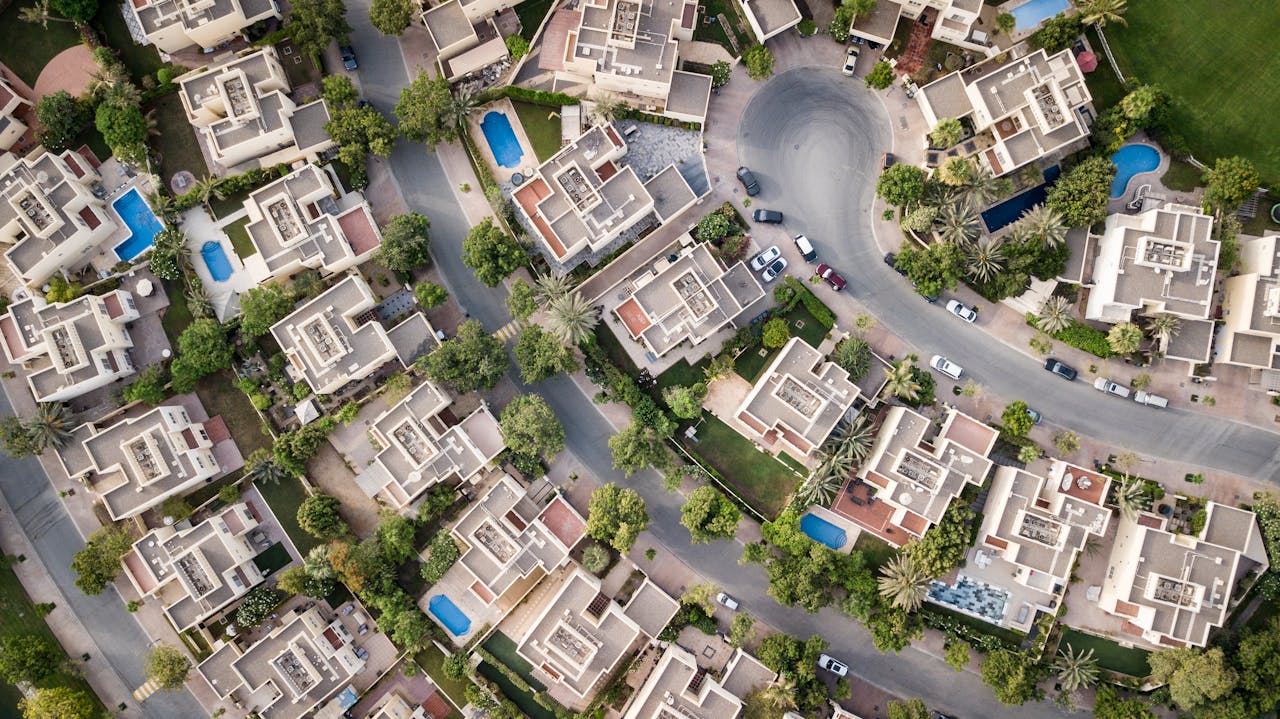 heros-img Explore a stunning aerial view of a residential area in Dubai with lush greenery and swimming pools.